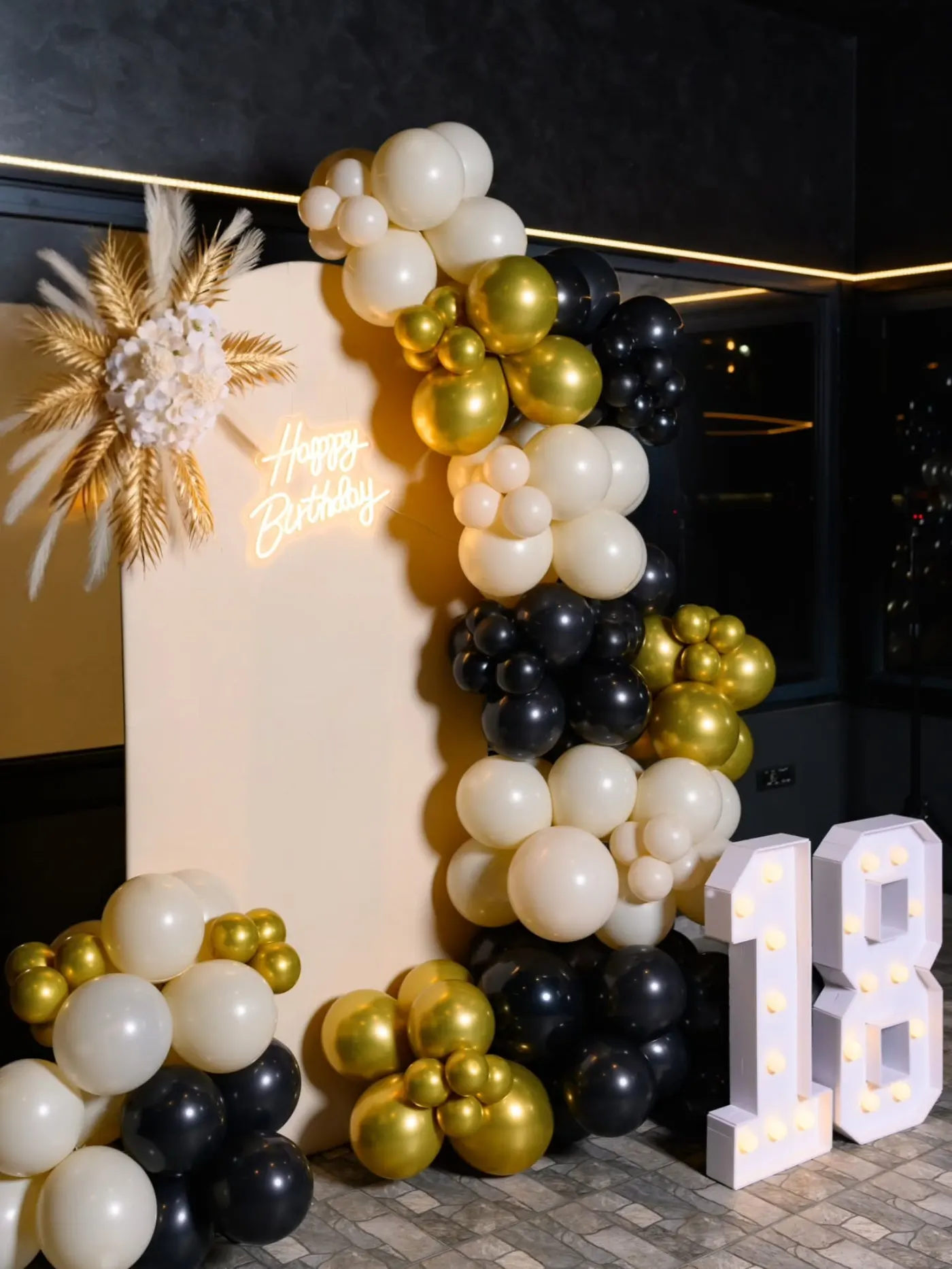 Crno-zlatna dekoracija punoletstva sa balon girlandom, neonom i svetlećim brojem 18